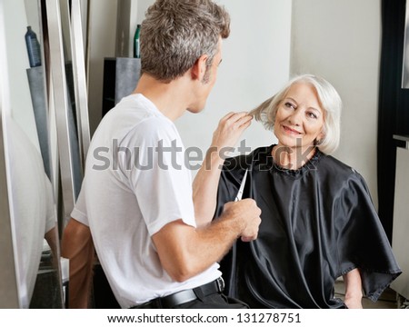 Senior female client instructing male hairdresser in beauty salon