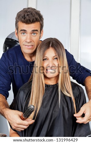 Portrait of mature hair dresser and client making faces at salon