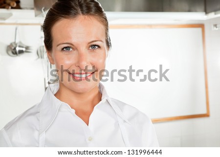 Portrait of happy female chef in industrial kitchen