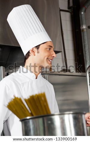 Side view of young male chef standing in industrial kitchen