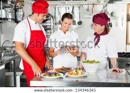 Chefs looking for recipe on a tablet computer while cooking at kitchen