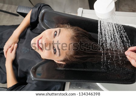Portrait of female client getting hair wash at beauty salon