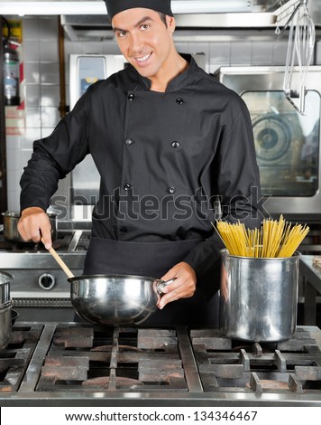 Portrait of happy chef preparing pasta in industrial kitchen