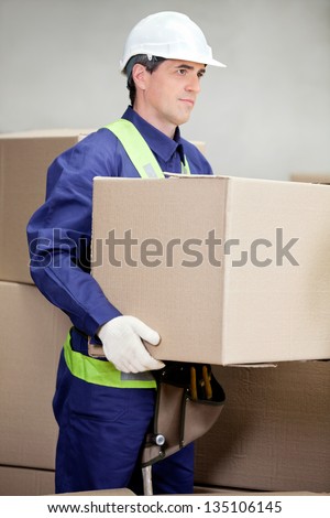 Portrait of foreman lifting cardboard box at warehouse