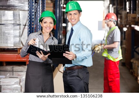 Portrait of supervisors with clipboard and foreman unloading cardboard boxes at warehouse