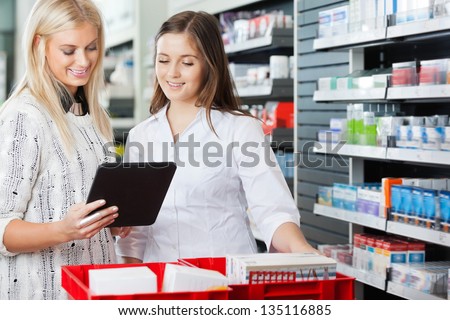Young pharmacist helping customer in pharmacy with digital tablet