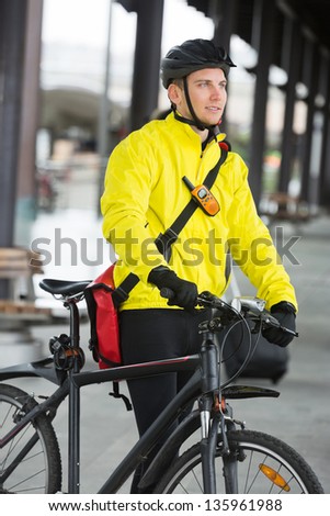 Young man in protective gear with bicycle and bag looking away