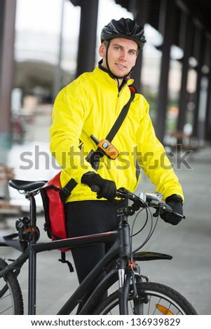 Portrait of young male cyclist in protective gear with bag