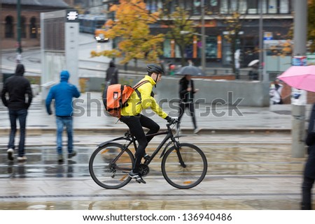 Side View Of Young Man In Protective Gear With Backpack Riding Bicycle On Street