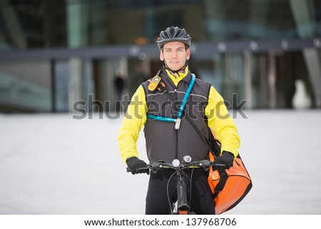 Portrait of young male cyclist in protective gear carrying courier delivery bag