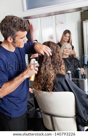 Hairstylists setting up female customer\'s hair at beauty parlor
