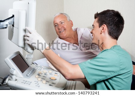 Male Technician Showing Ultrasound Machine\'S Monitor To Senior Patient