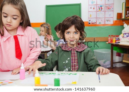 Portrait of little boy painting with female friend in art class