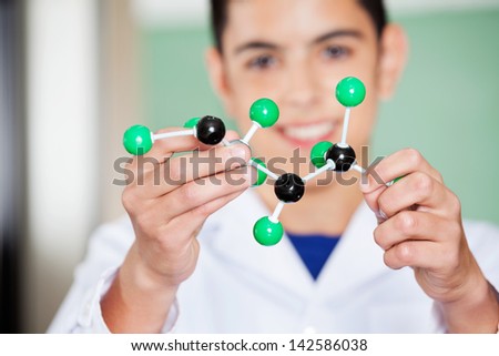 Closeup of schoolboy examining molecular structure in lab