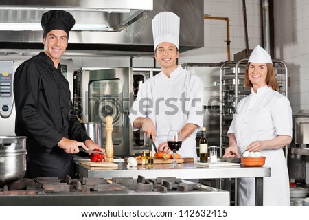 Portrait of happy chefs working in industrial kitchen