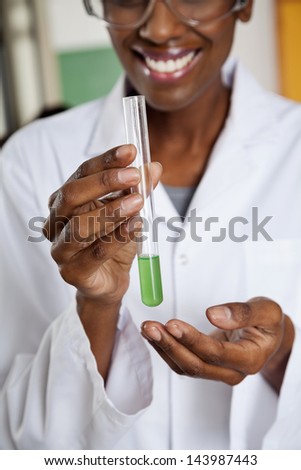 Midsection of young teacher holding chemical solution in test tube at lab