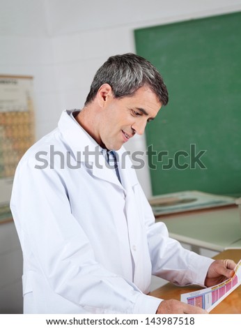 Mature male professor reading paper at desk in science lab