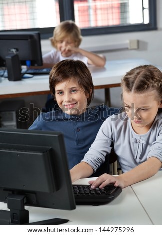 Little boy and girl using desktop PC together in computer lab