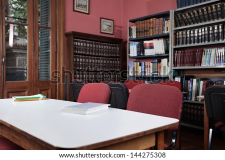 Empty chairs at table with bookshelves in library