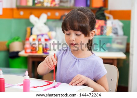 Cute little girl painting at desk in classroom Cute little girl painting at desk in classroom