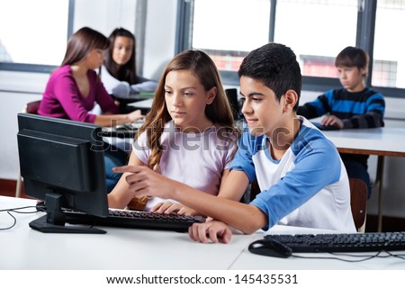 Male And Female Teenage Friends Using Computer In Lab