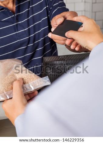 Cropped image of female customer making credit card payment at cash counter while receiving product
