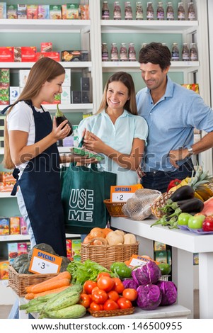 Young saleswoman showing vegetable packet to couple in supermarket