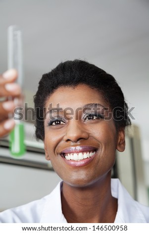 Closeup of happy young teacher looking at chemical solution in test tube
