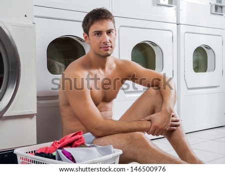 Portrait of semi nude man with laundry basket waiting to wash clothes