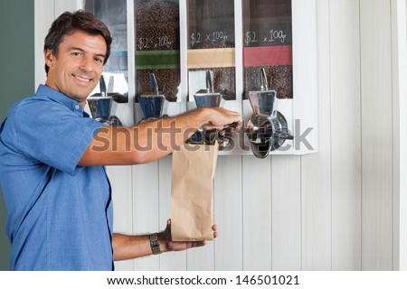 Portrait of mid adult man buying coffee beans from vending machine at grocery store