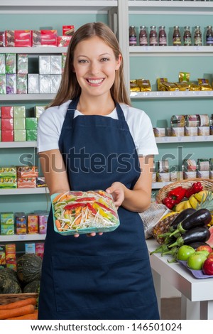 Portrait Of Beautiful Saleswoman Holding Vegetable Packet In Grocery Store