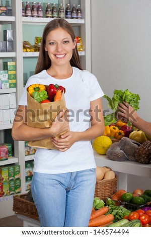 Portrait of beautiful young woman with vegetable bag in supermarket