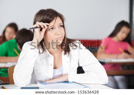 Thoughtful teenage girl looking away with students in background