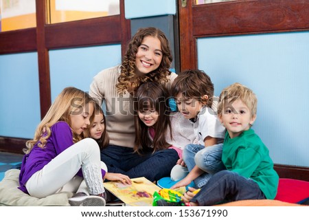 Happy teacher sitting with children on floor in classroom