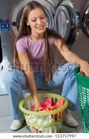 Beautiful young woman with basket of clothes at laundry