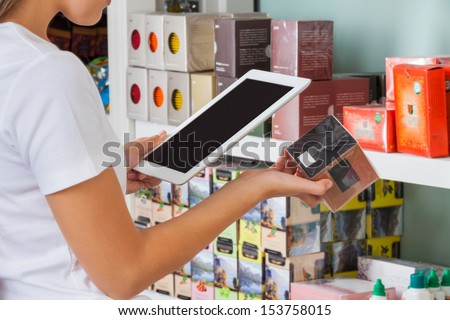 Midsection of young woman scanning barcode through digital tablet at supermarket