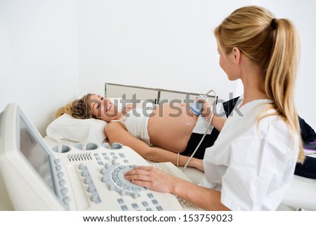 Young Pregnant Woman Getting Ultrasound From Female Doctor In Clinic