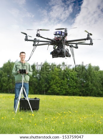 Young man with remote control flying UAV helicopter in park