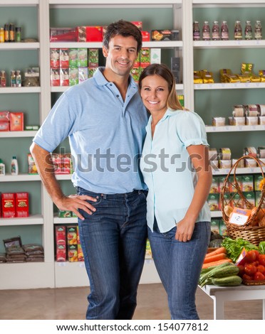 Portrait of mid adult couple standing against shelves in grocery store
