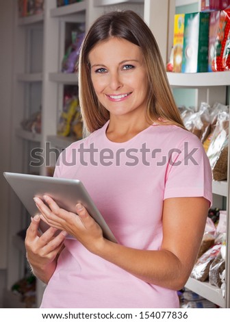 Portrait of happy mid adult woman with digital tablet in supermarket