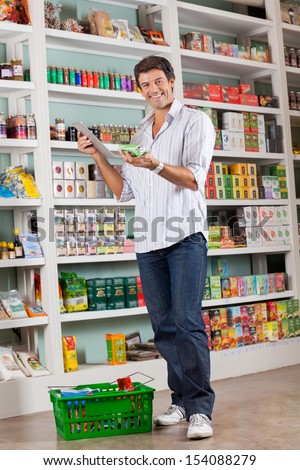 Full length portrait of happy mid adult man checking list on digital tablet in grocery store