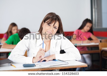 Portrait of female student sitting at desk in classroom