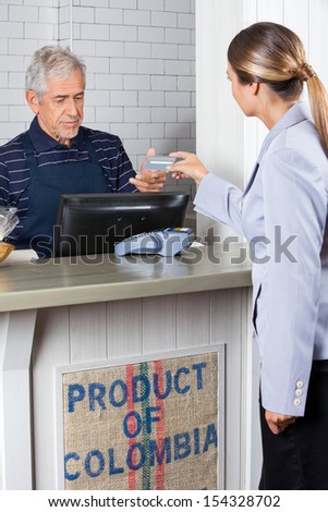 Female customer making payment by credit card at cash counter in supermarket