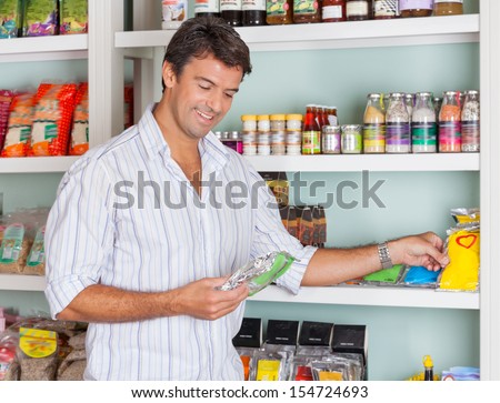 Happy mid adult man selecting food packets in grocery store