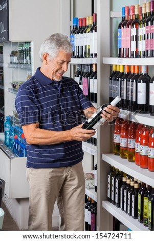 Happy senior man buying alcohol at supermarket