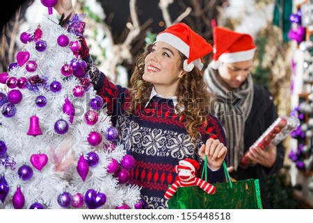 Happy young woman shopping for Christmas decorations with man in store