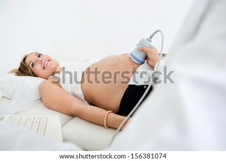 Happy pregnant woman getting ultrasound scan from obstetrician in clinic