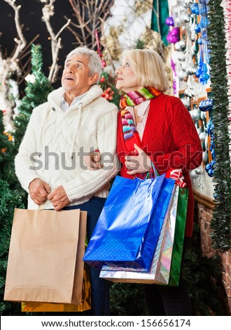 Senior couple with shopping bags looking up at Christmas store