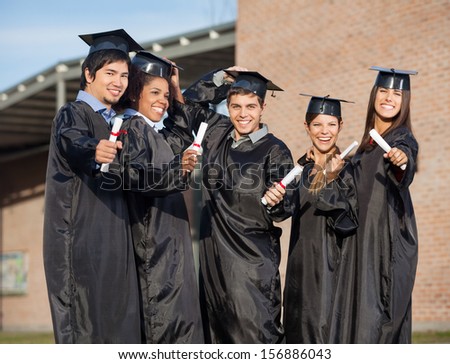Portrait of multiethnic graduate students holding certificates on university campus