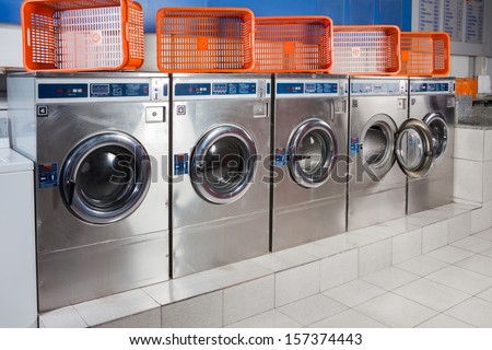 Washing Machines And Empty Baskets In A Row At Laundromat